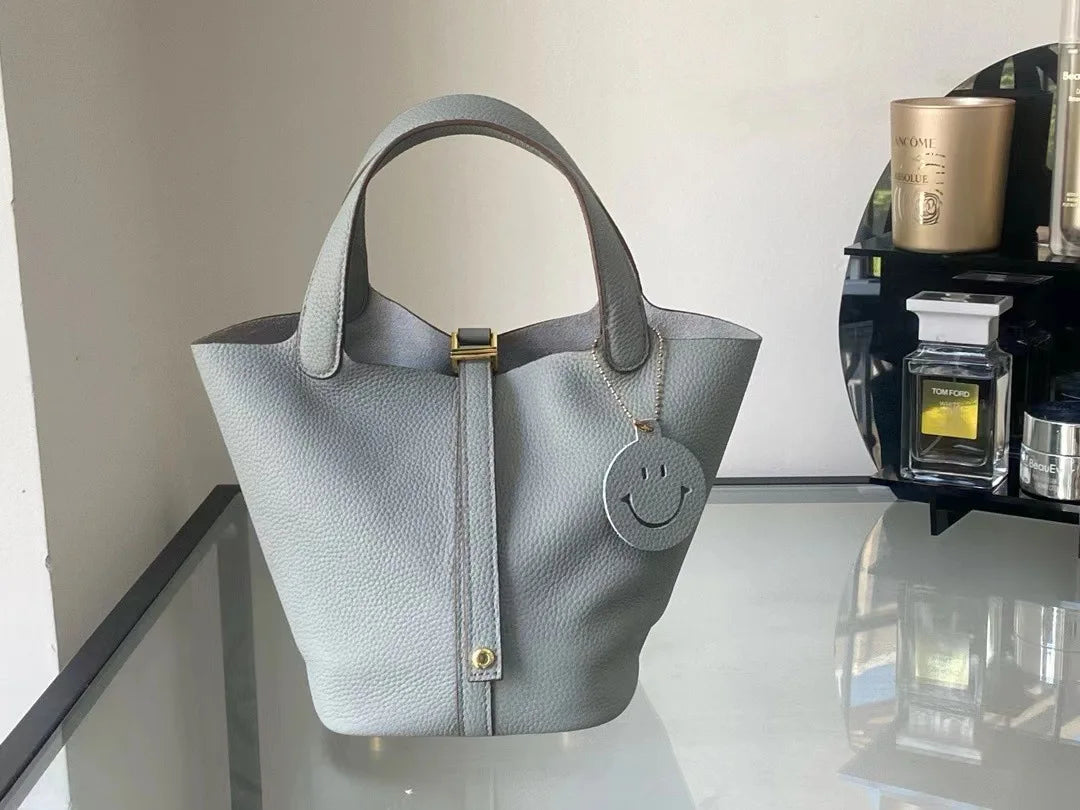New Leather Luxury Handbag, High-end in light grey color displayed on a glass table.