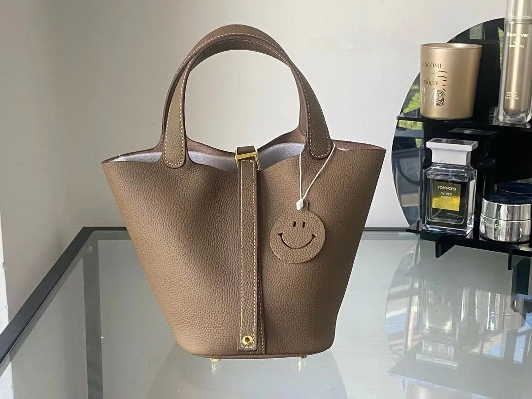New Leather Luxury Handbag, High-end in brown with a smiley charm on display.