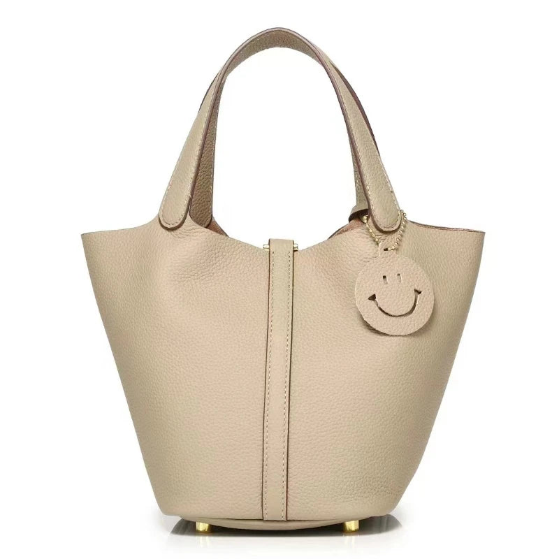 New Leather Luxury Handbag, High-end in beige color with smiley charm and bucket shape design.